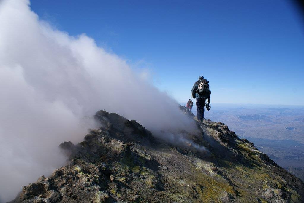 Científicos del INVOLCAN realizando medidas de emisión de gases en el borde del cráter principal del volcán Etna, Italia.